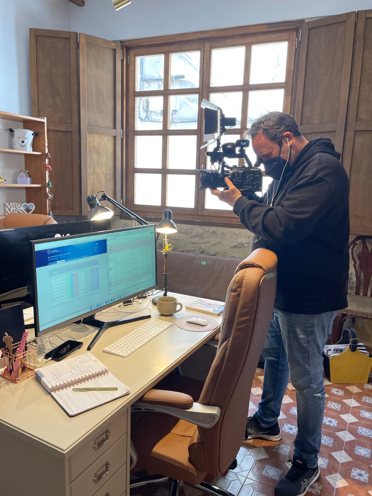 A camera operator filming beside an office desk